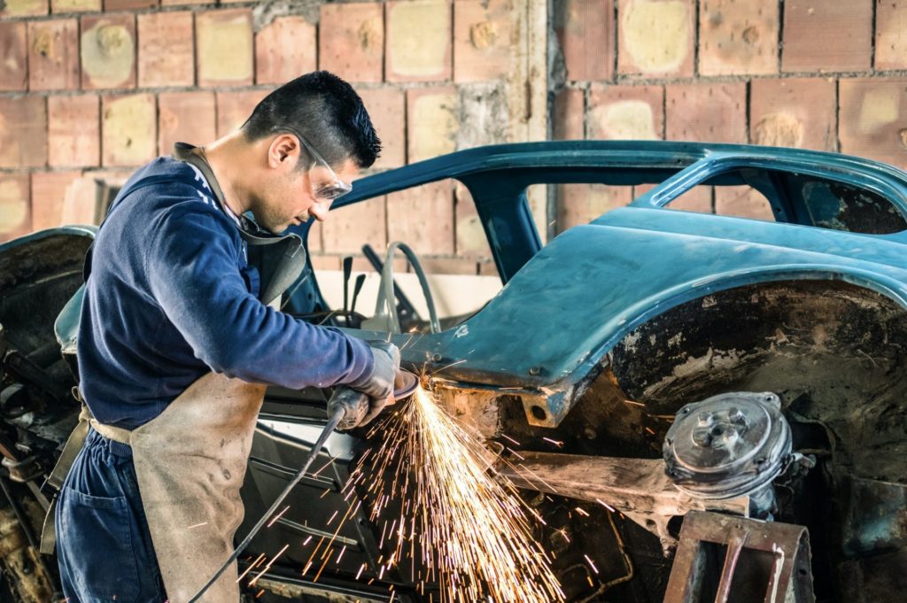 young man mechanical worker repairing an old vintage car body in New Orleans